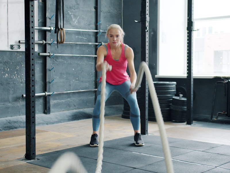 Woman doing battle rope exercises in a gym